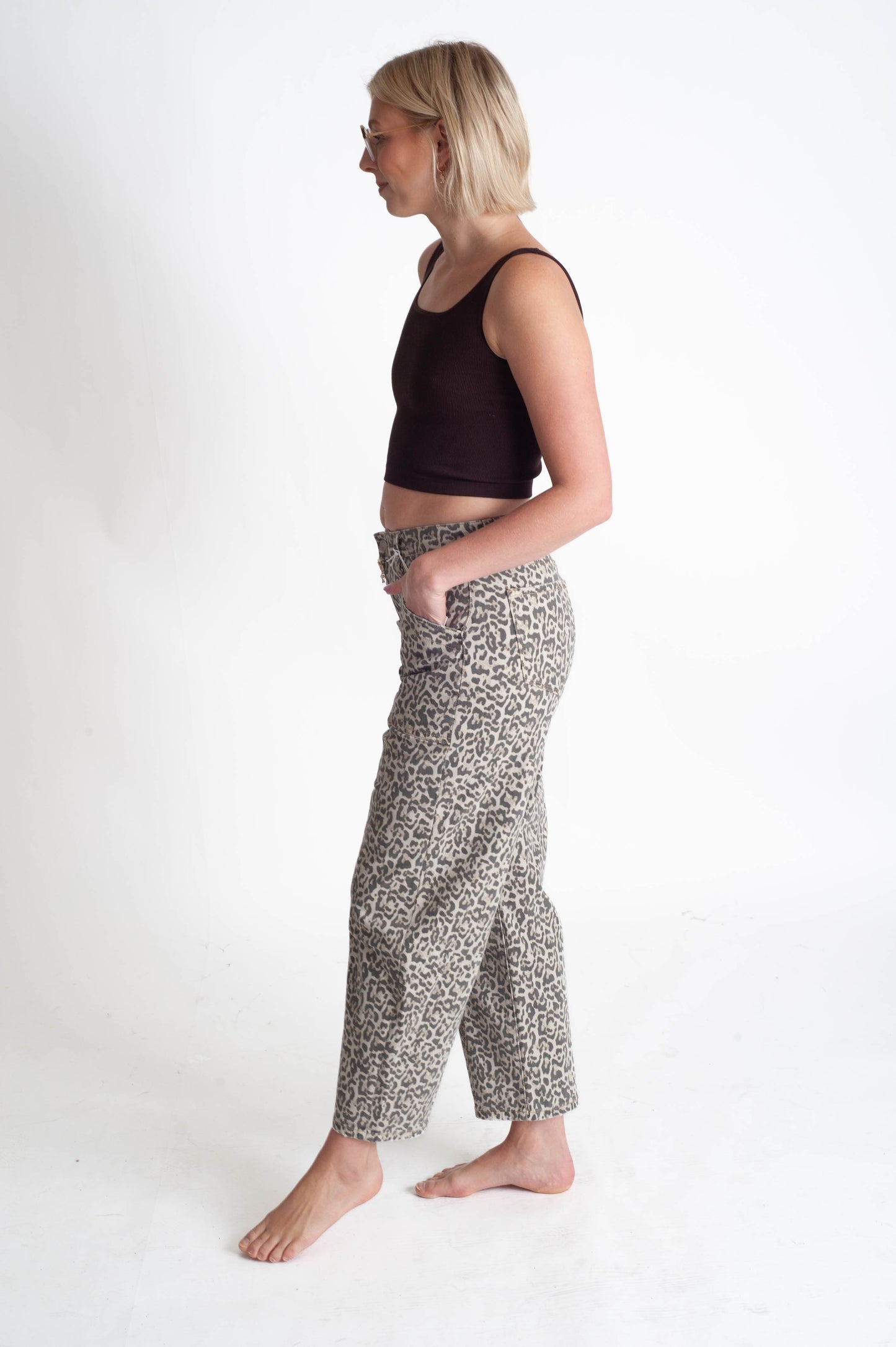 Woman wearing a dark top and leopard patterned pants on a white background