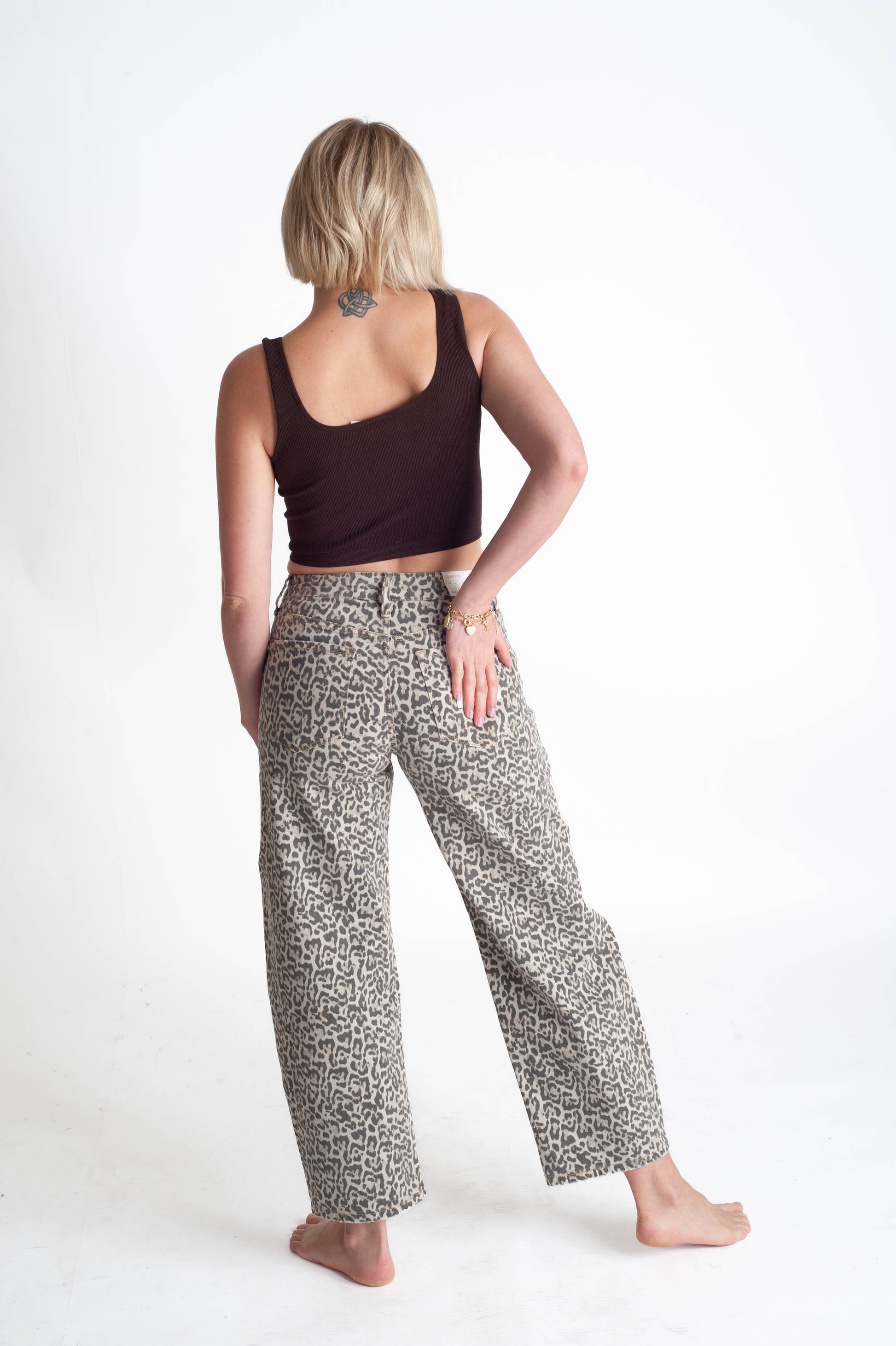 Woman wearing a dark top and leopard patterned pants on a white background