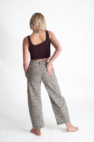Woman wearing a dark top and leopard patterned pants on a white background