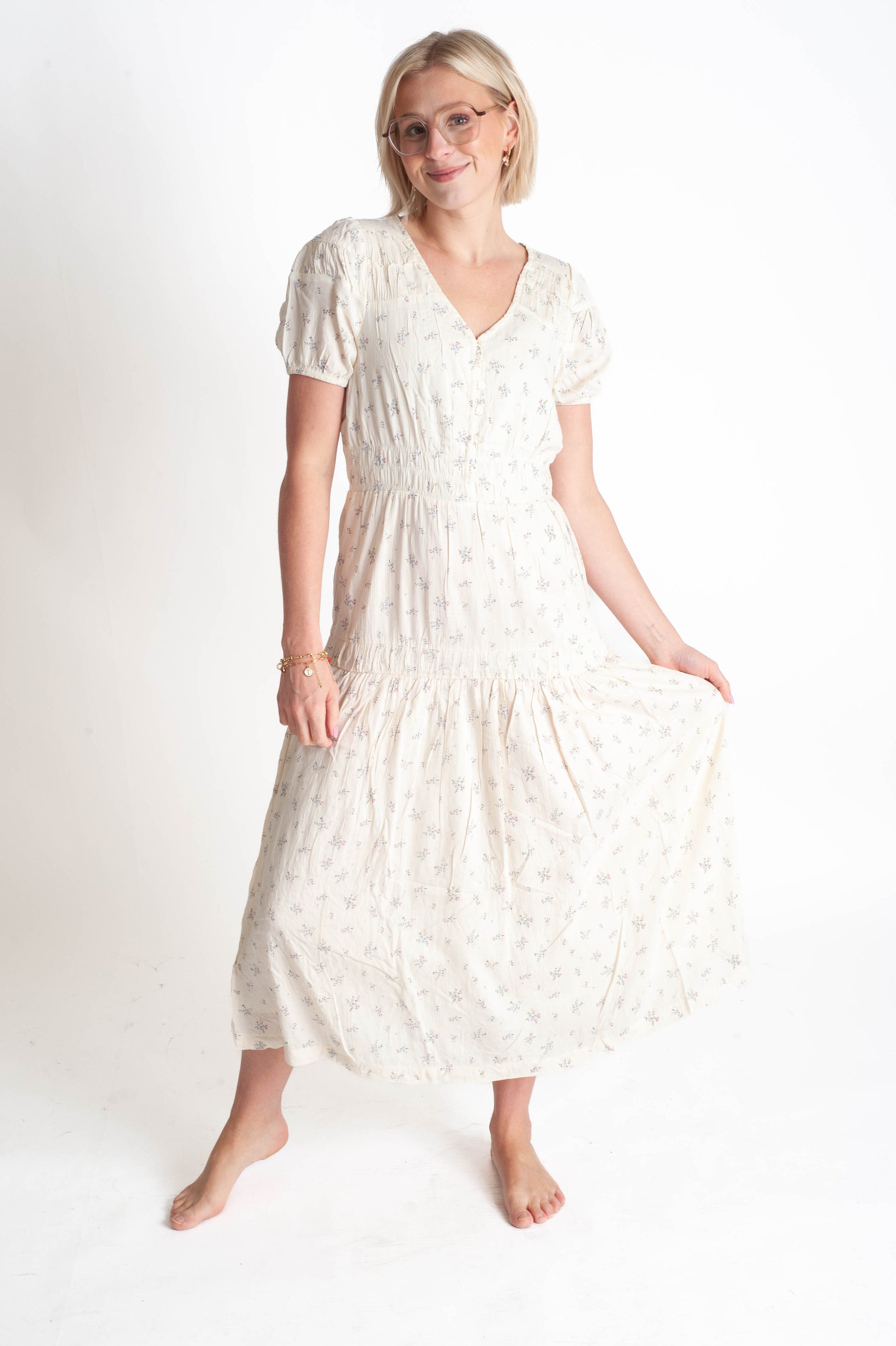 Woman wearing a white dress with a subtle pattern on a plain background