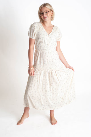 Woman wearing a white dress with a subtle pattern on a plain background
