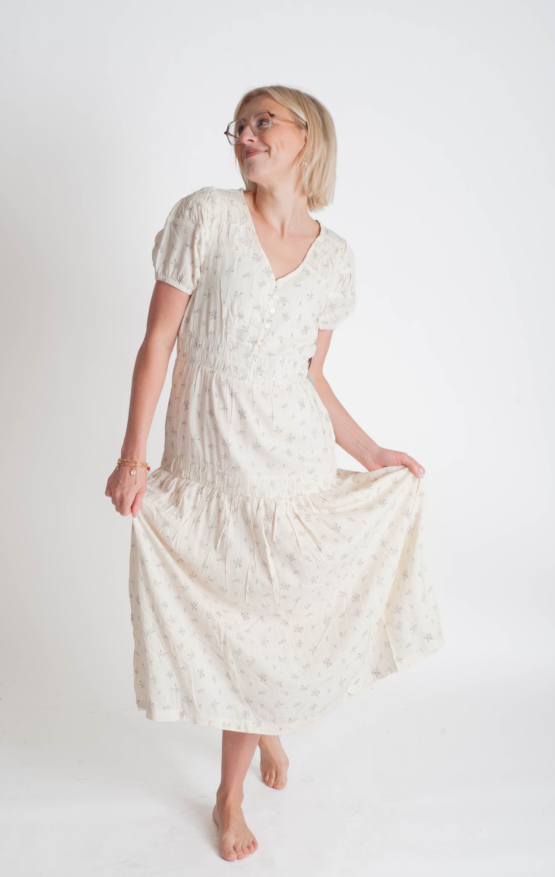 Woman wearing a white dress with a subtle pattern on a plain background