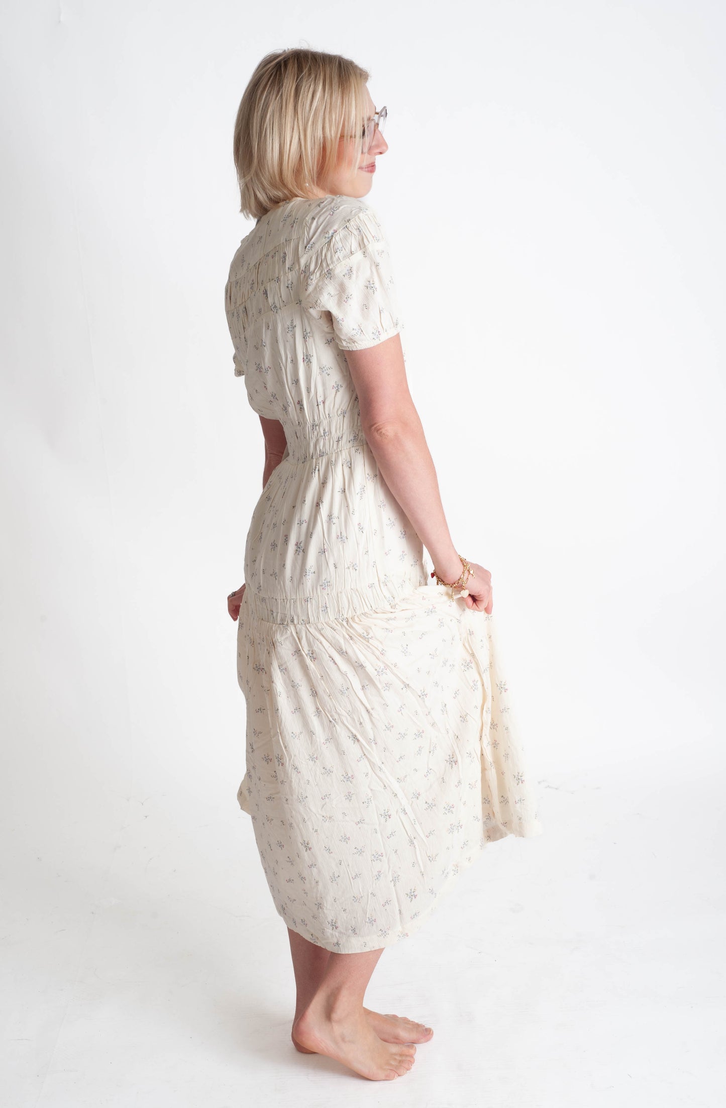 Woman wearing a white floral dress on a plain background