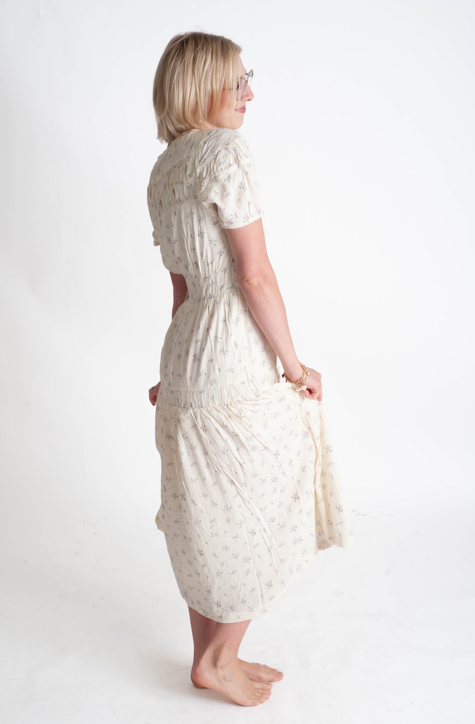 Woman wearing a white floral dress on a plain background