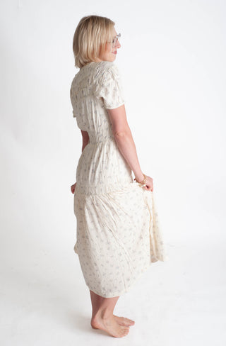 Woman wearing a white floral dress on a plain background