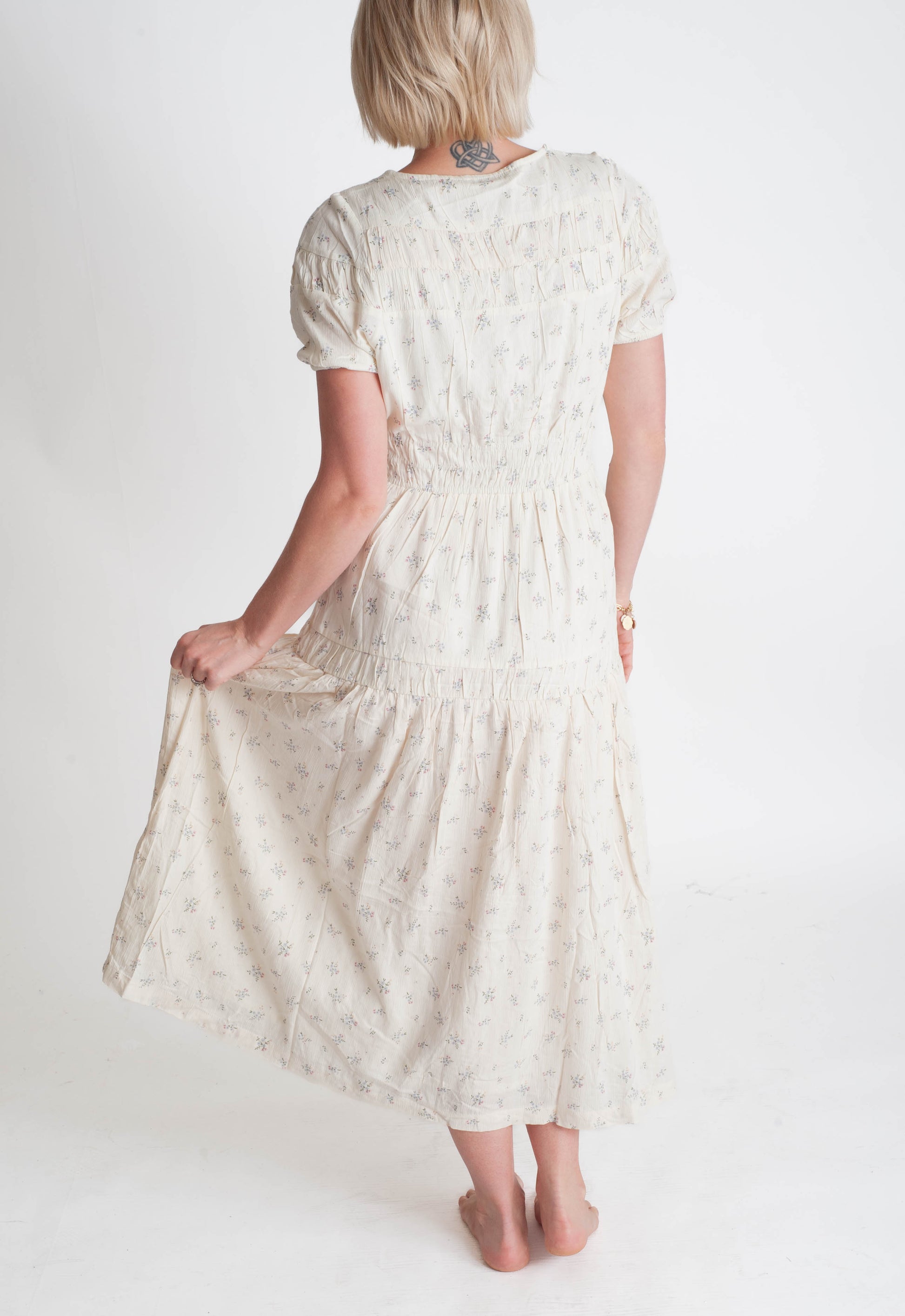 Woman wearing a white floral dress on a plain background