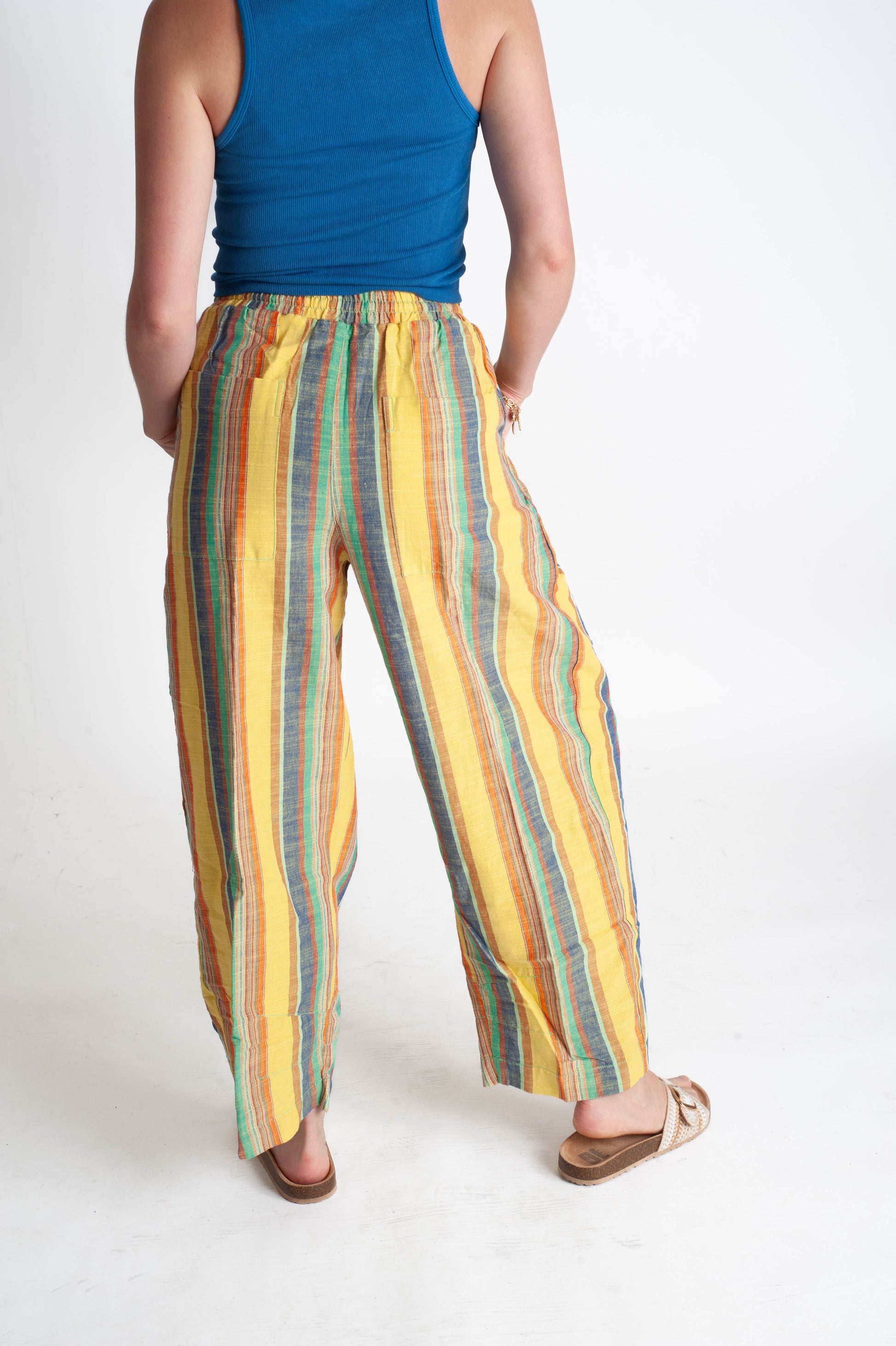 Person wearing a blue top and colorful striped pants on a white background