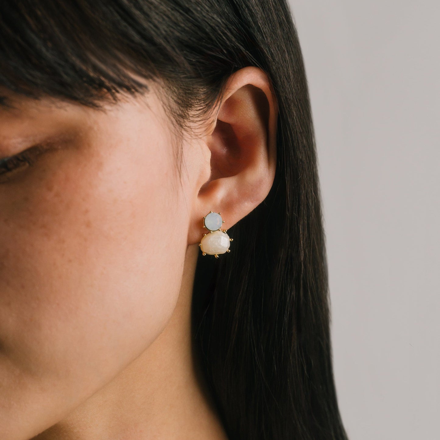 Close-up of a person wearing earrings with a neutral background