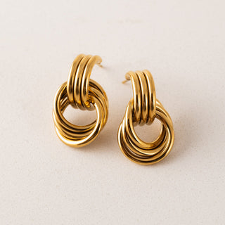 Pair of gold hoop earrings on a light beige background