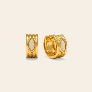 Gold hoop earrings with opal stones on a beige background