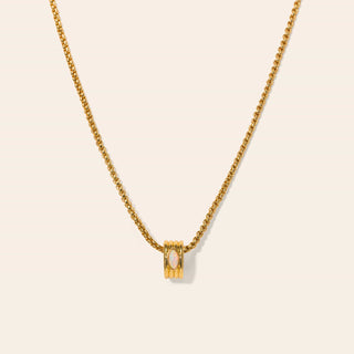 Gold necklace with a small pendant on a beige background