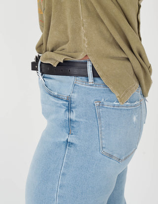 Light blue jeans worn with a green shirt on a white background