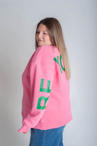 Person wearing a pink sweatshirt with 'BE YOURSELF' text on a white background