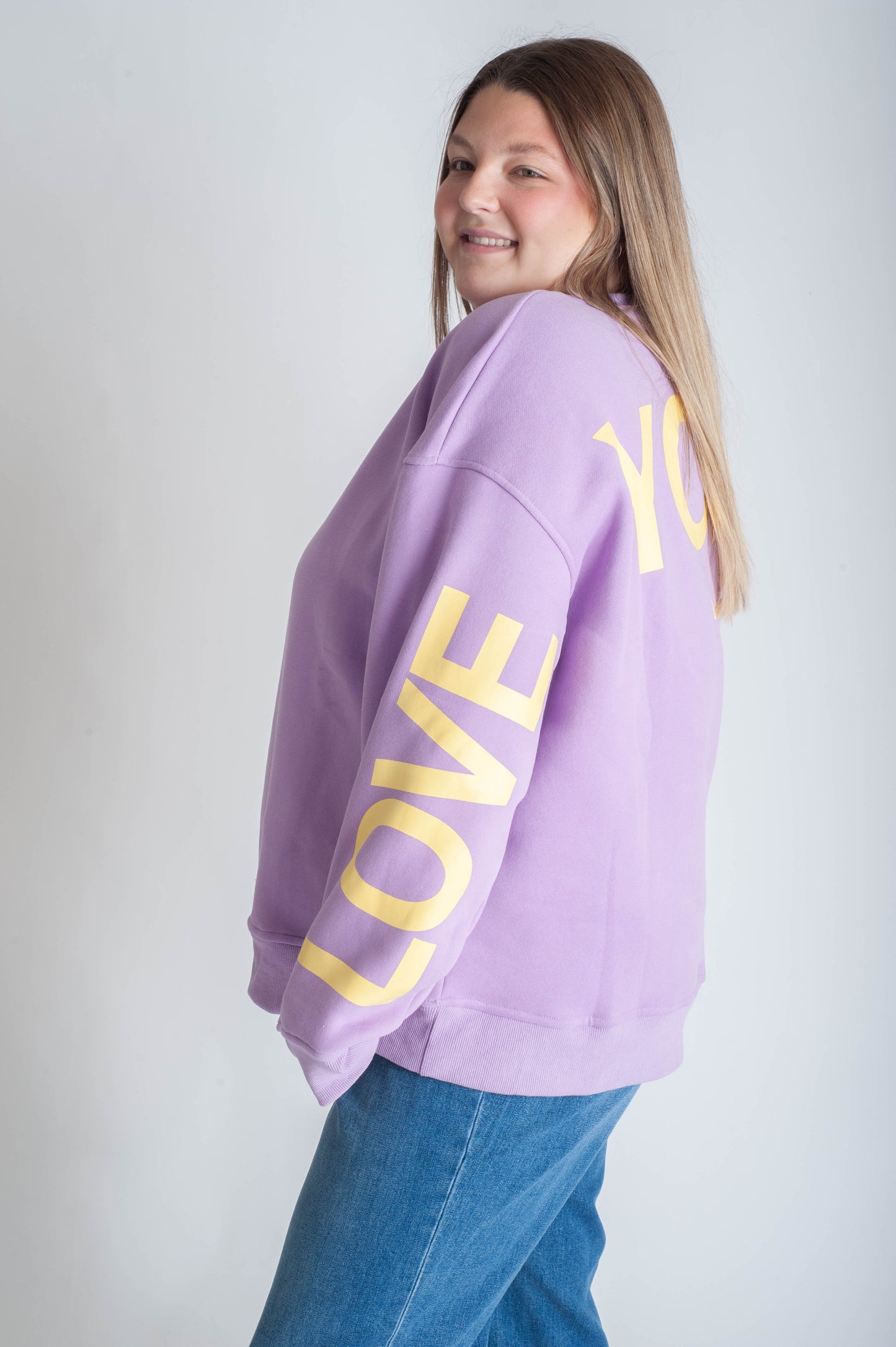 Person wearing a purple sweatshirt with 'LOVE YOU' in yellow text on a plain background