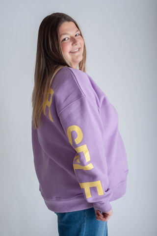 Person wearing a purple sweatshirt with 'BE YOURSELF' text on a white background
