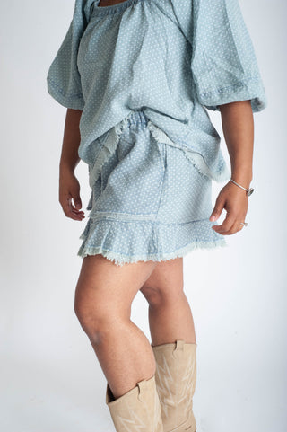 Light blue patterned outfit with ruffled skirt and beige knee-high boots on a white background