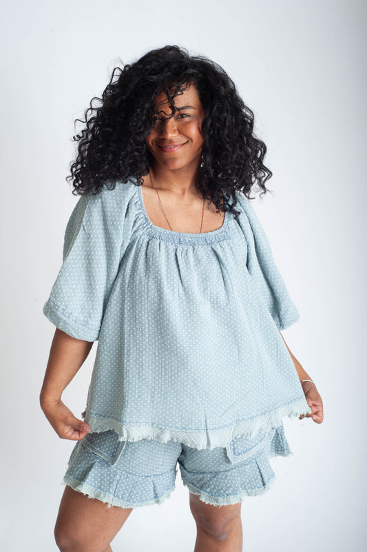 Woman wearing a light blue textured top and shorts set on a white background