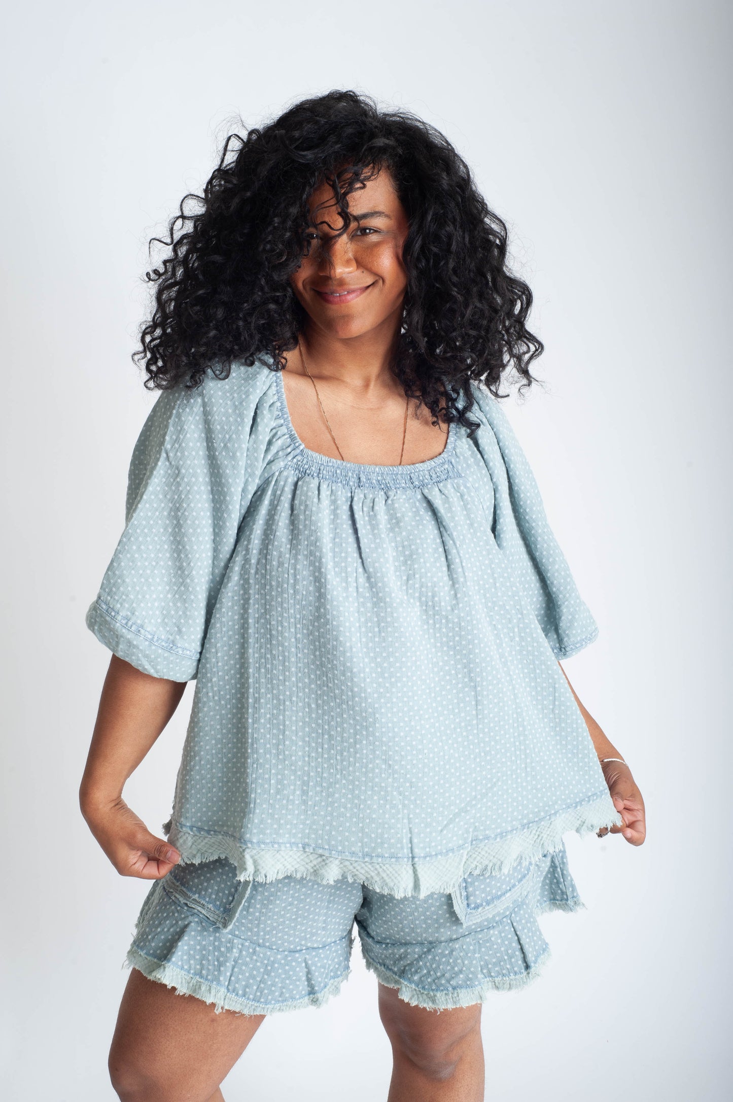 Woman wearing a light blue textured top and shorts set on a white background