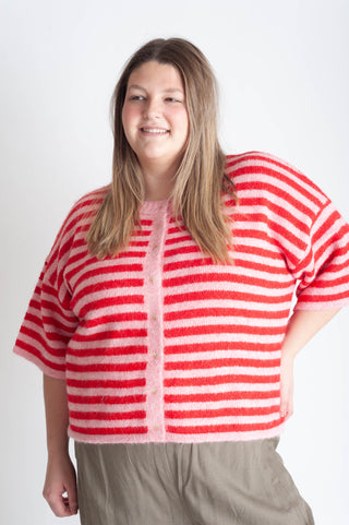 Women wearing a pink and red striped cardigan on a white background. 