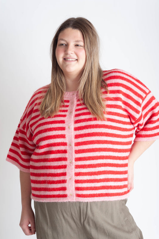 Women wearing a pink and red striped cardigan on a white background. 