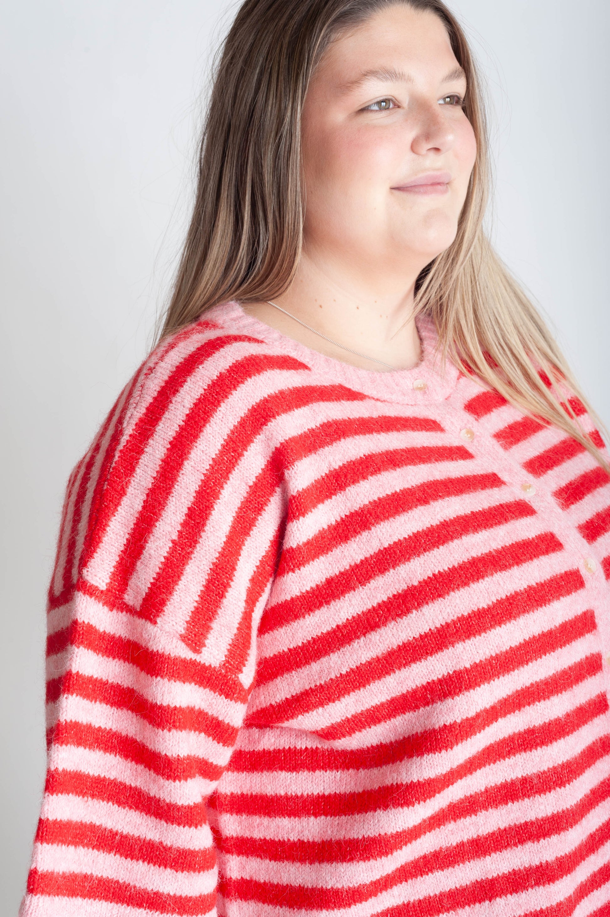 Person wearing a red and white striped sweater against a plain background
