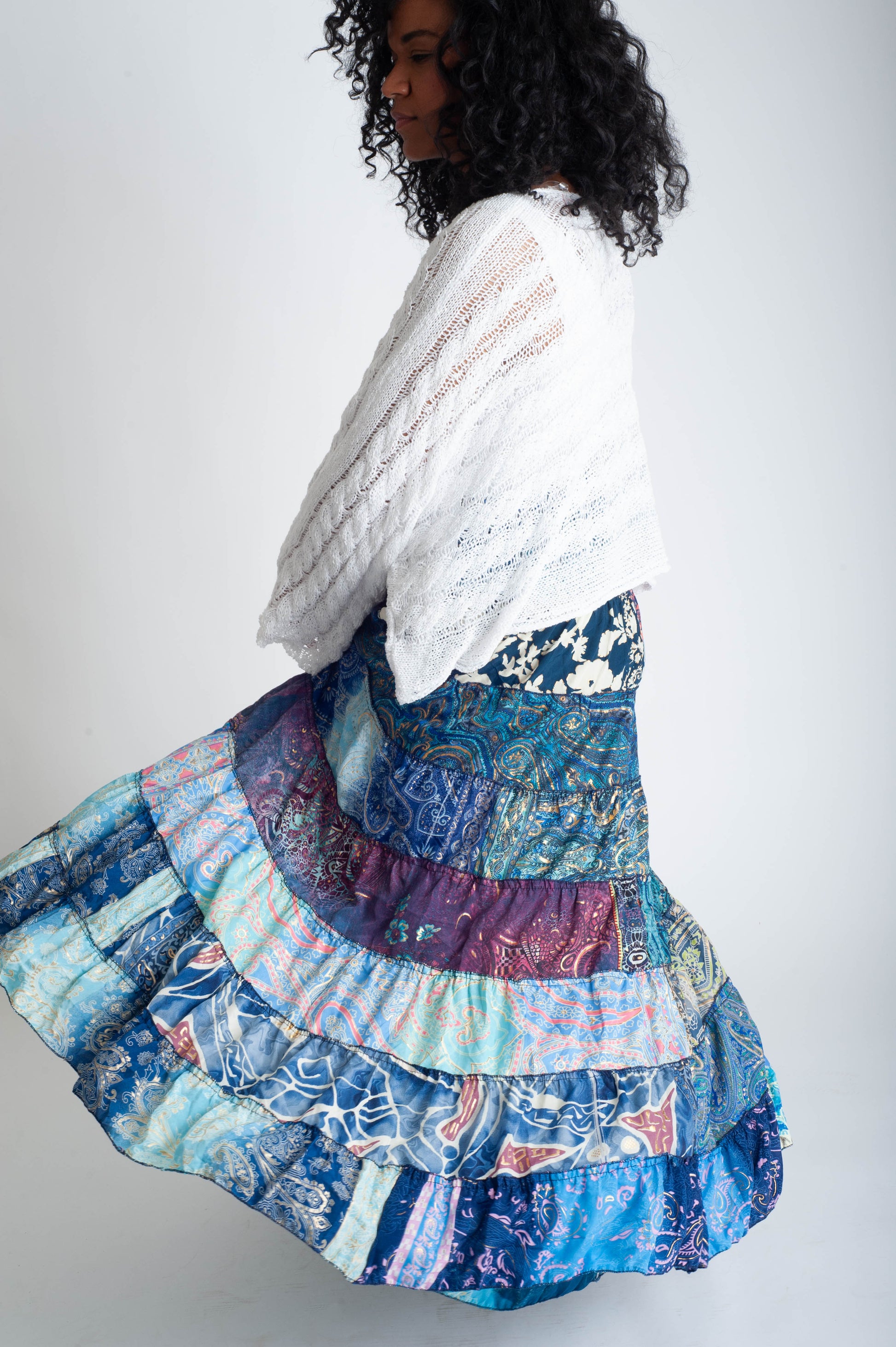 Woman wearing a colorful, layered skirt with a white top against a plain background