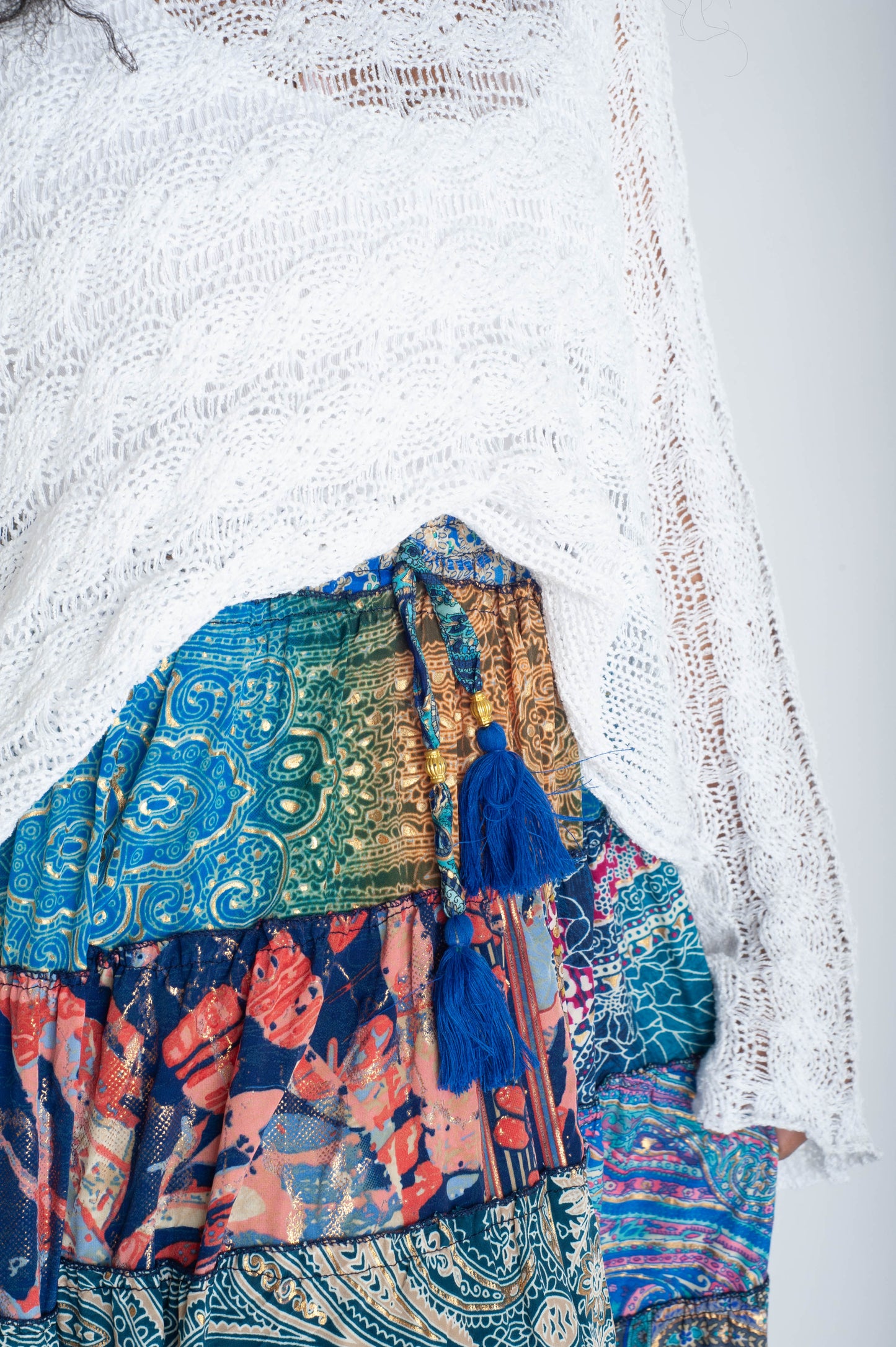 Colorful patterned fabric with tassels on a textured white background