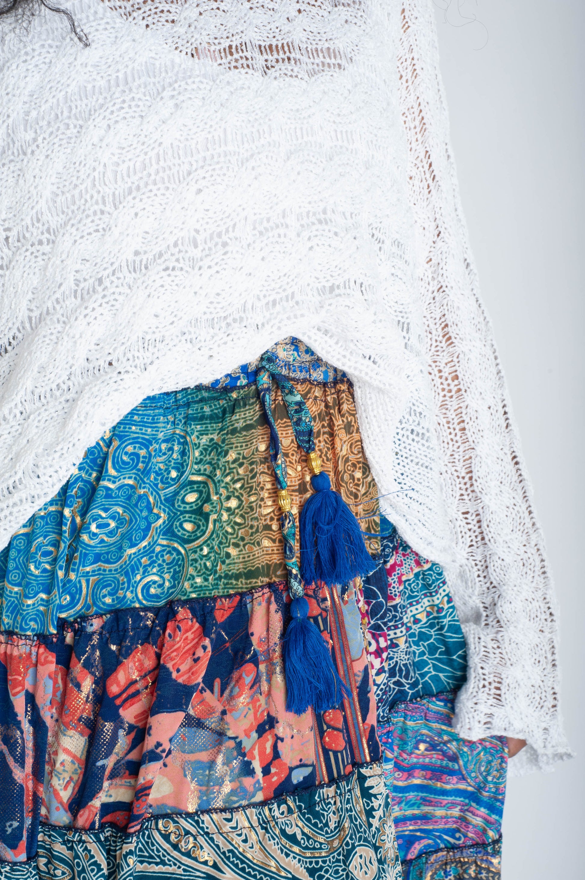 Colorful patterned fabric with tassels on a textured white background