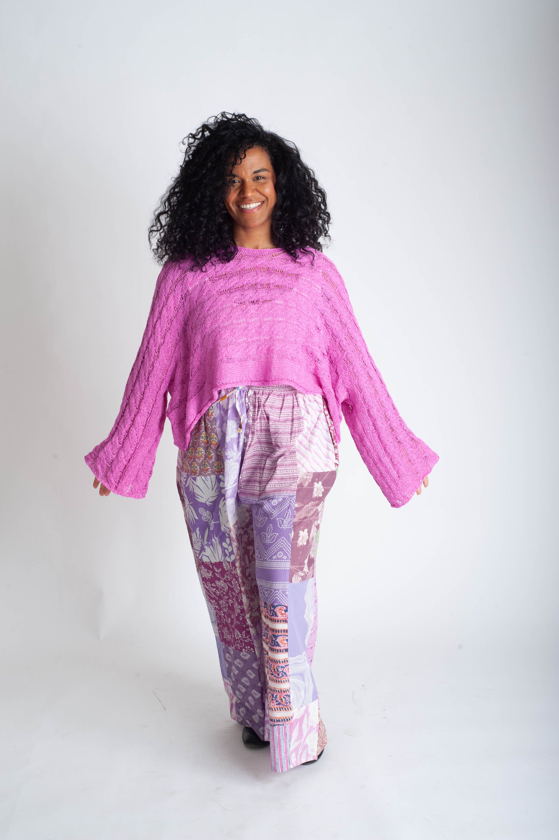 Woman wearing a pink top and patterned pants on a white background