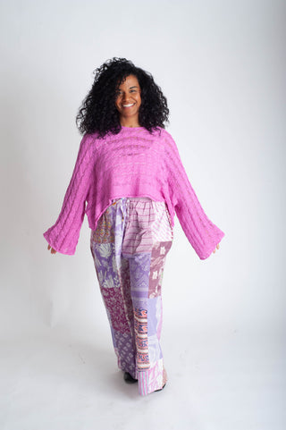 Woman wearing a pink top and patterned pants on a white background