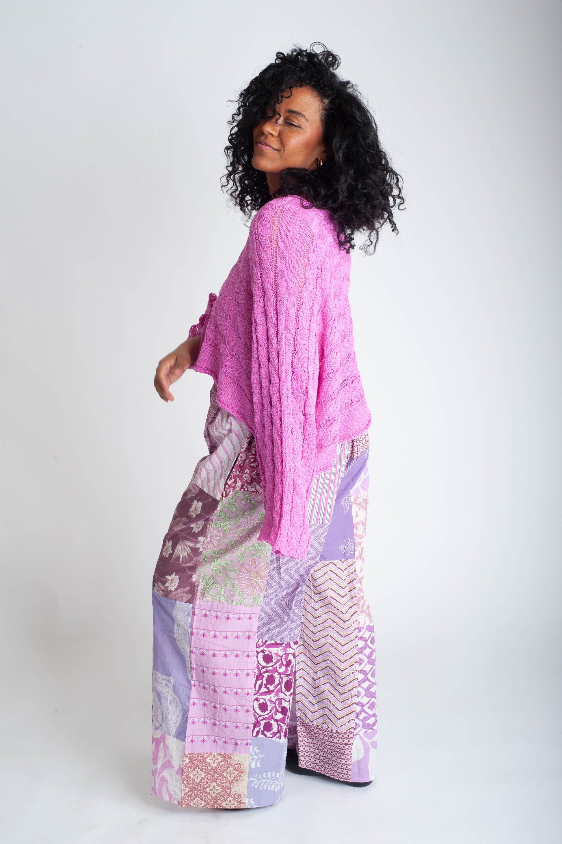 Woman wearing a pink top and patterned pants on a white background