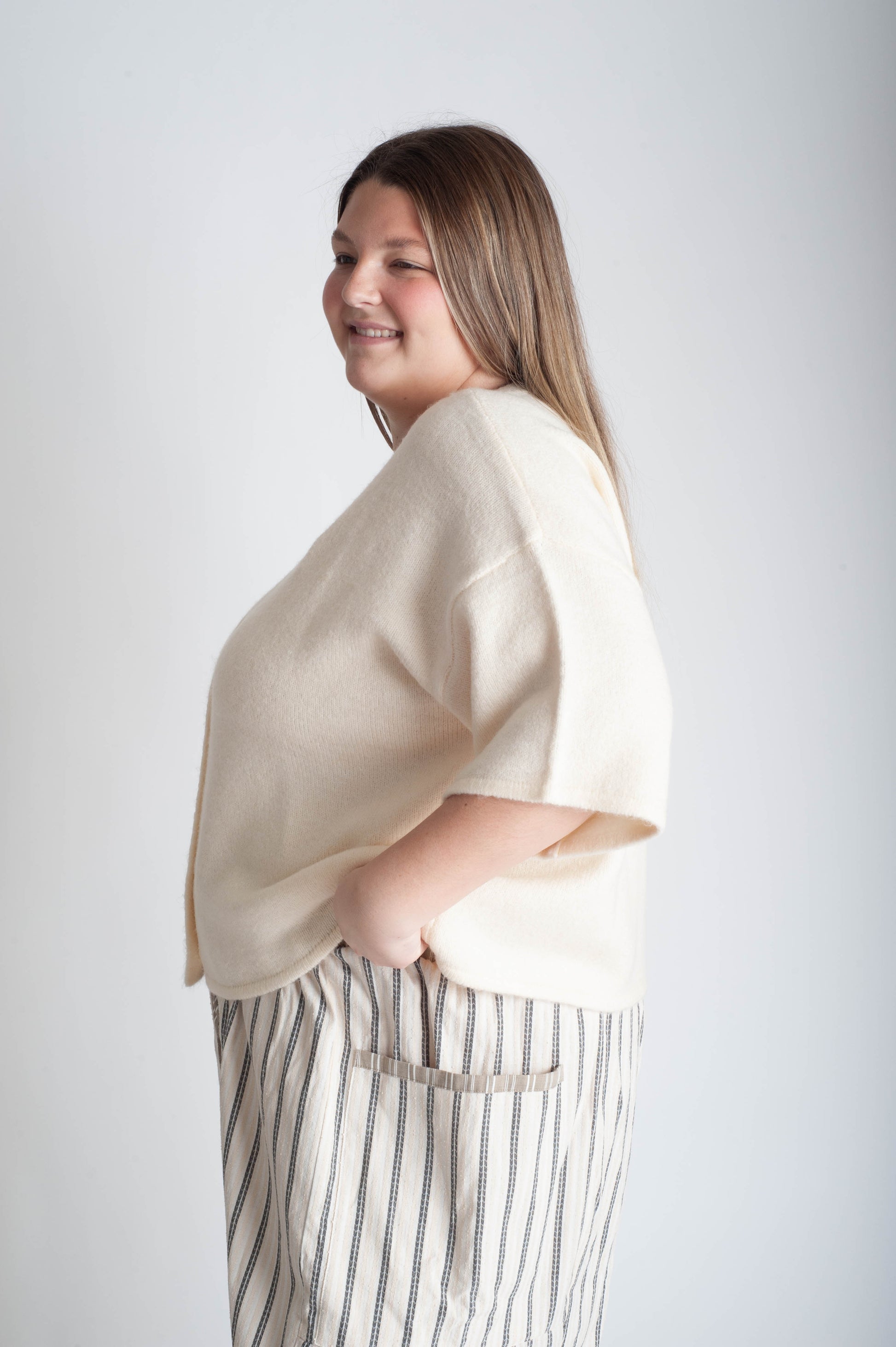 Women wearing a beige button up cardigan and blue floral skirt on a white background.