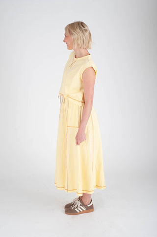 Woman wearing a yellow dress standing against a white background