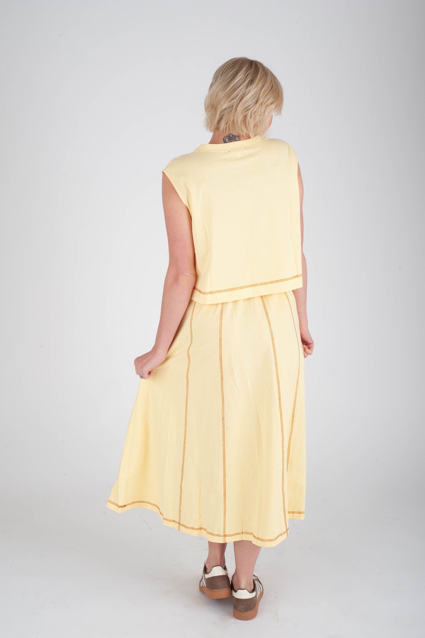 Woman wearing a yellow dress on a plain background