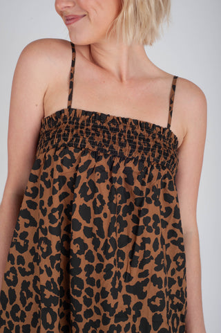 Woman wearing a leopard print dress against a plain background