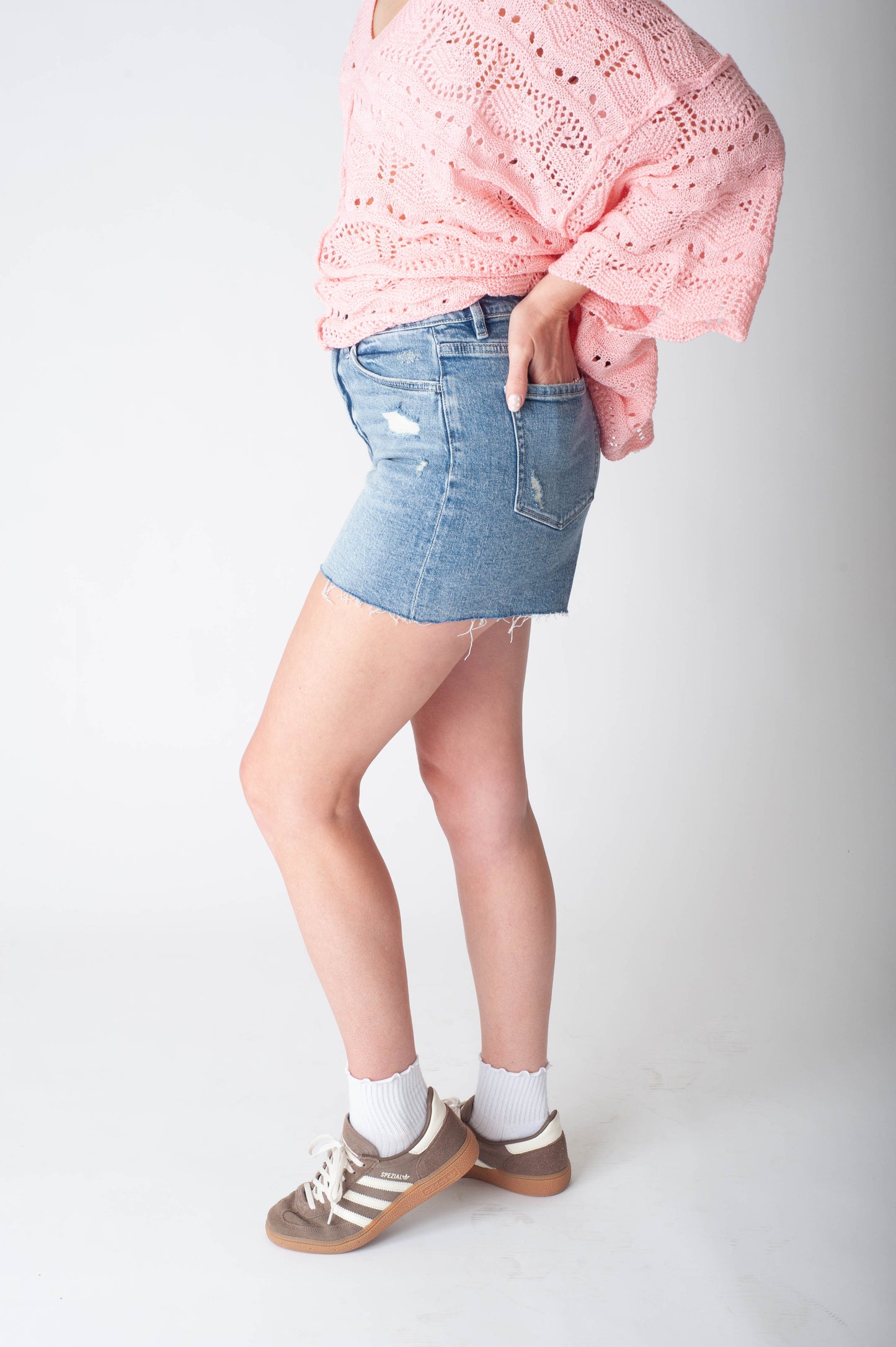 Women wearing long denim shorts and a pink sweater. 