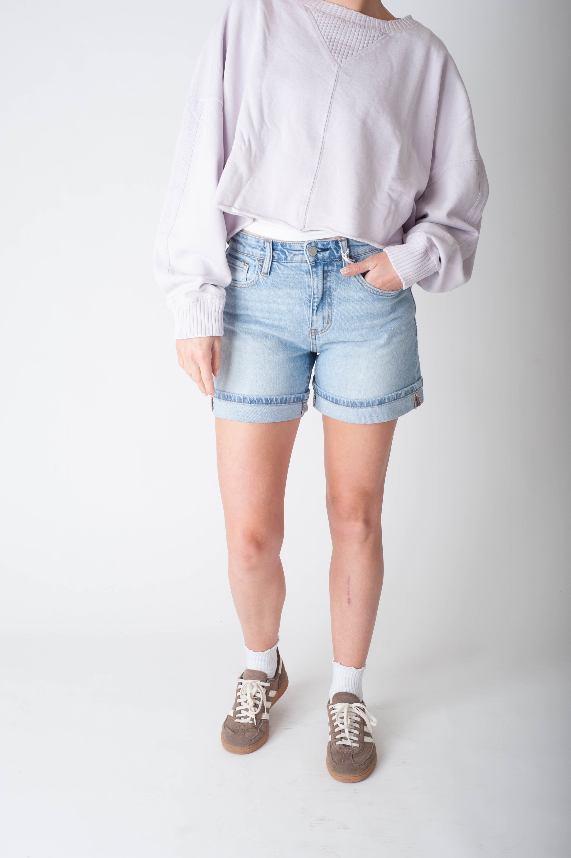 Women wearing long denim shorts and a purple sweater.