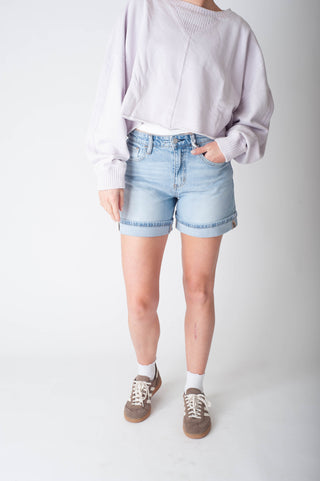 Women wearing long denim shorts and a purple sweater.