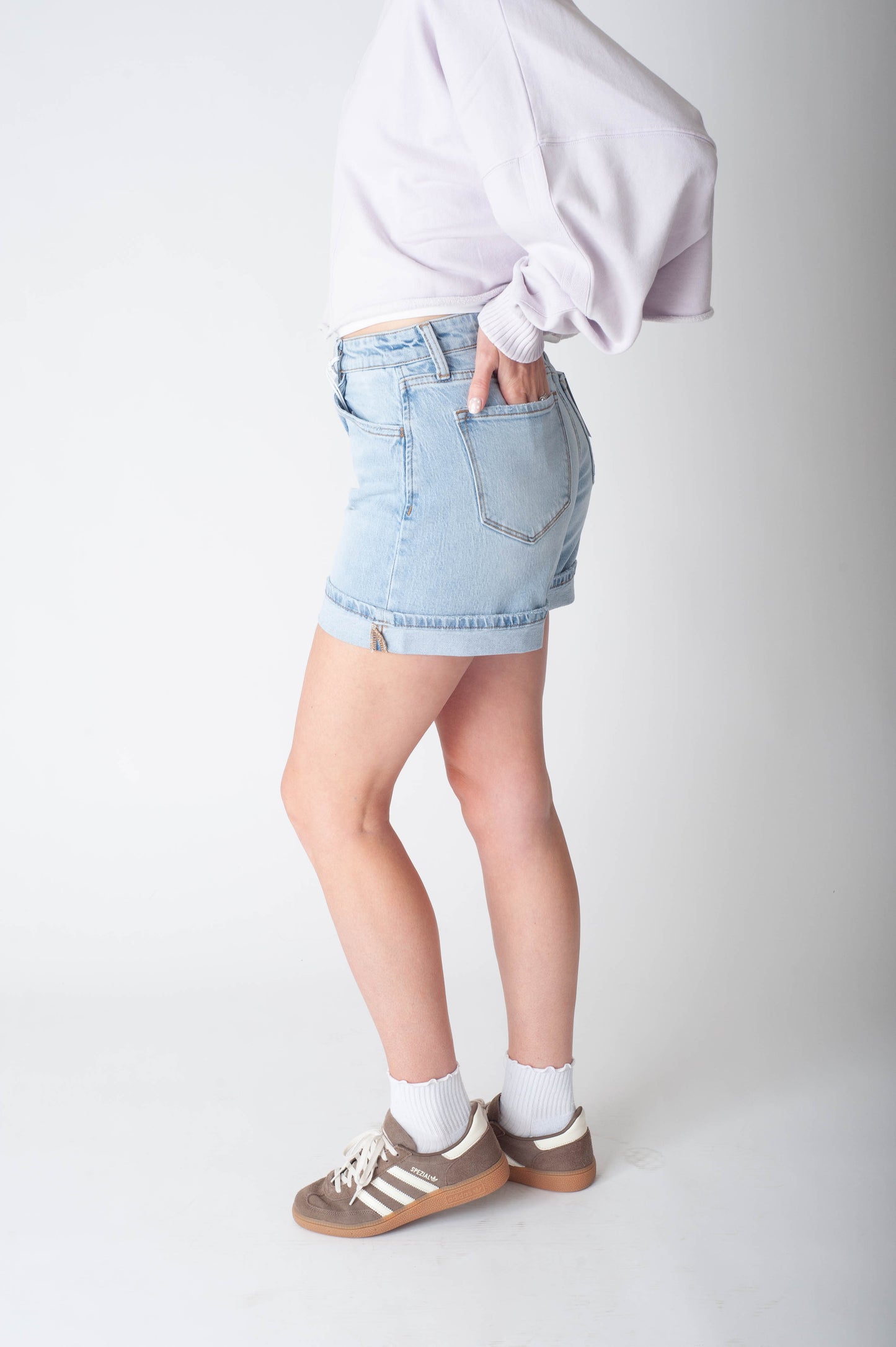 Women wearing long denim shorts and a purple sweater.