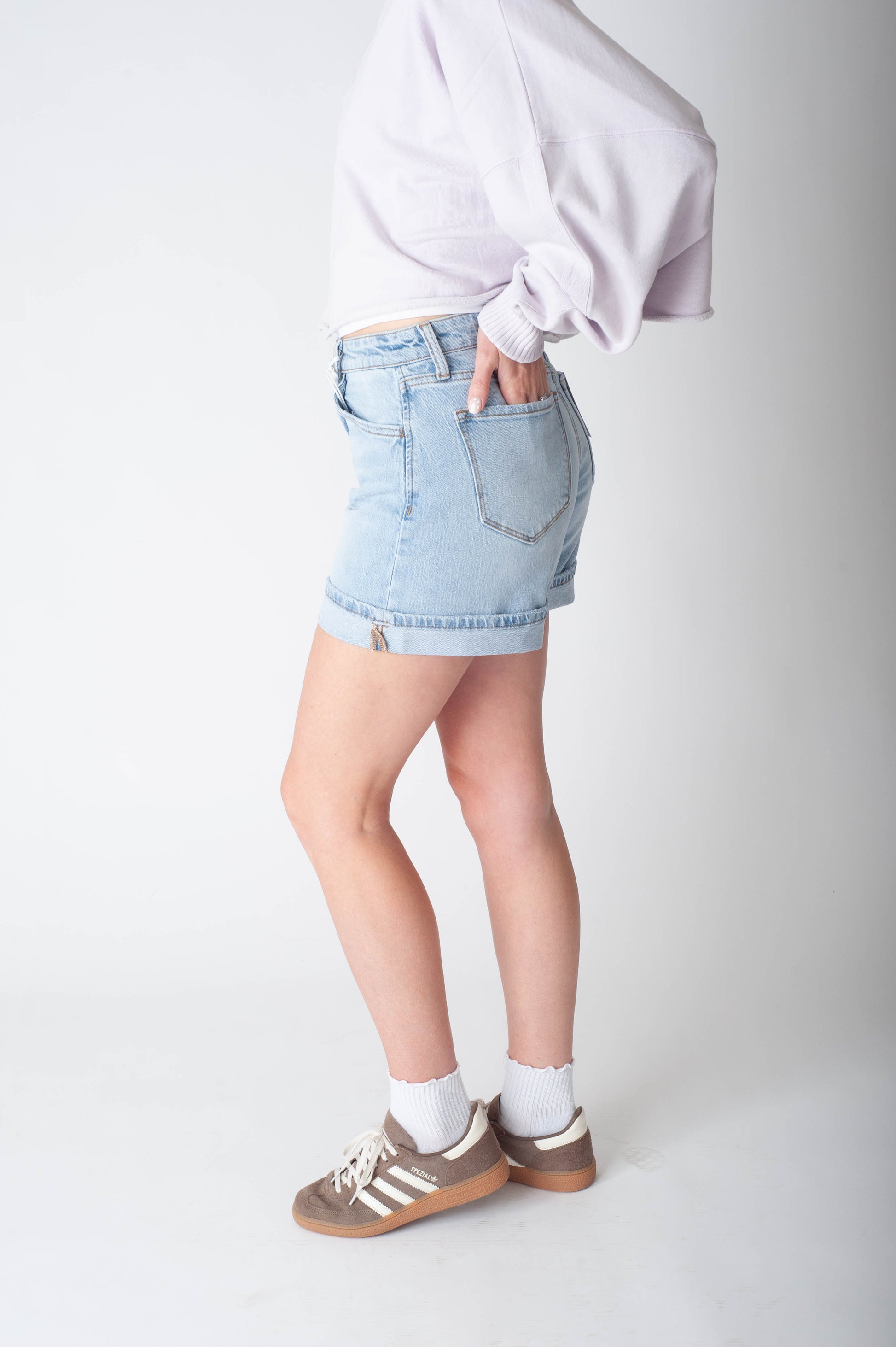 Women wearing long denim shorts and a purple sweater.