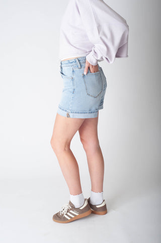 Women wearing long denim shorts and a purple sweater.