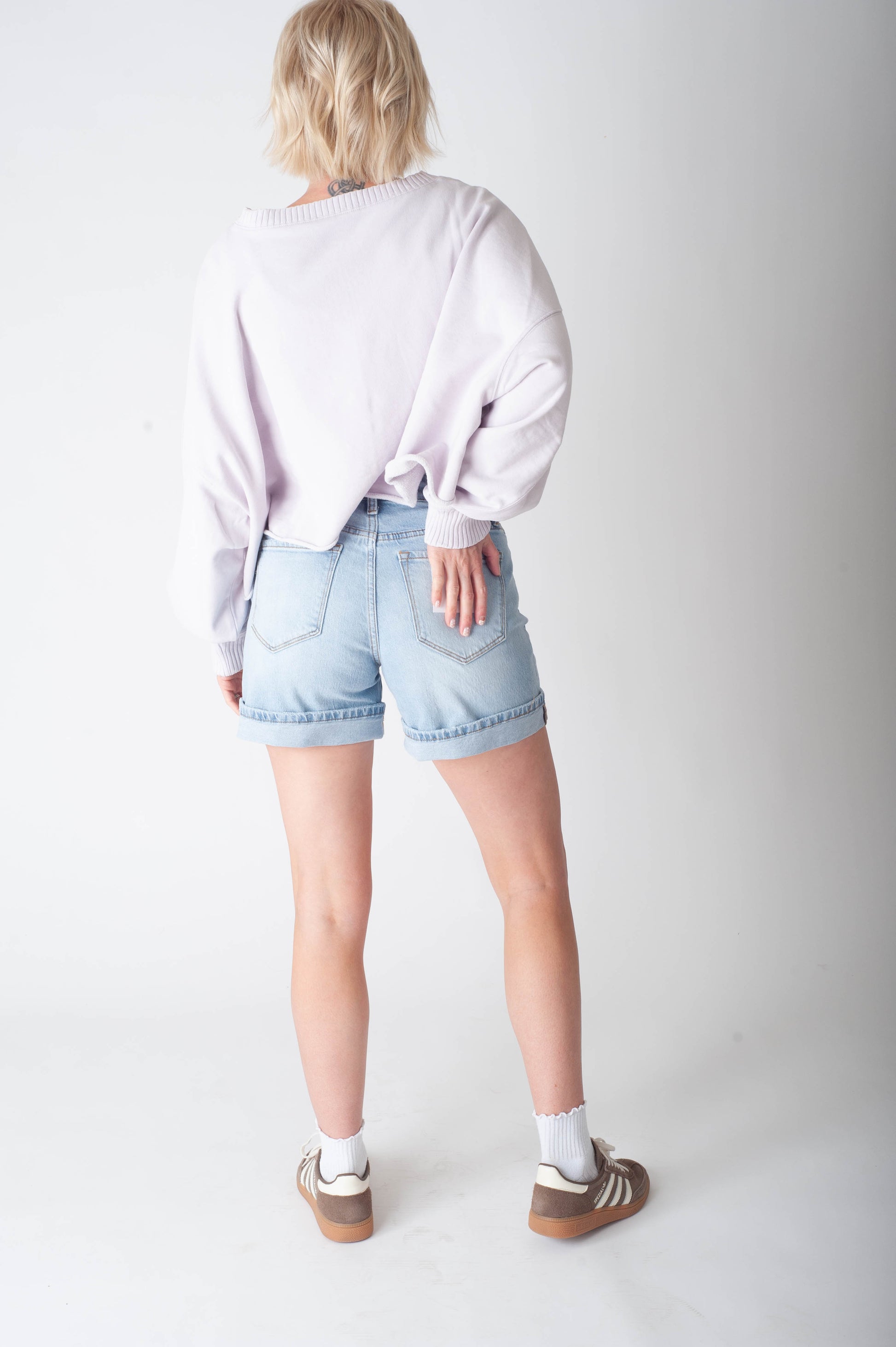 Women wearing long denim shorts and a purple sweater.