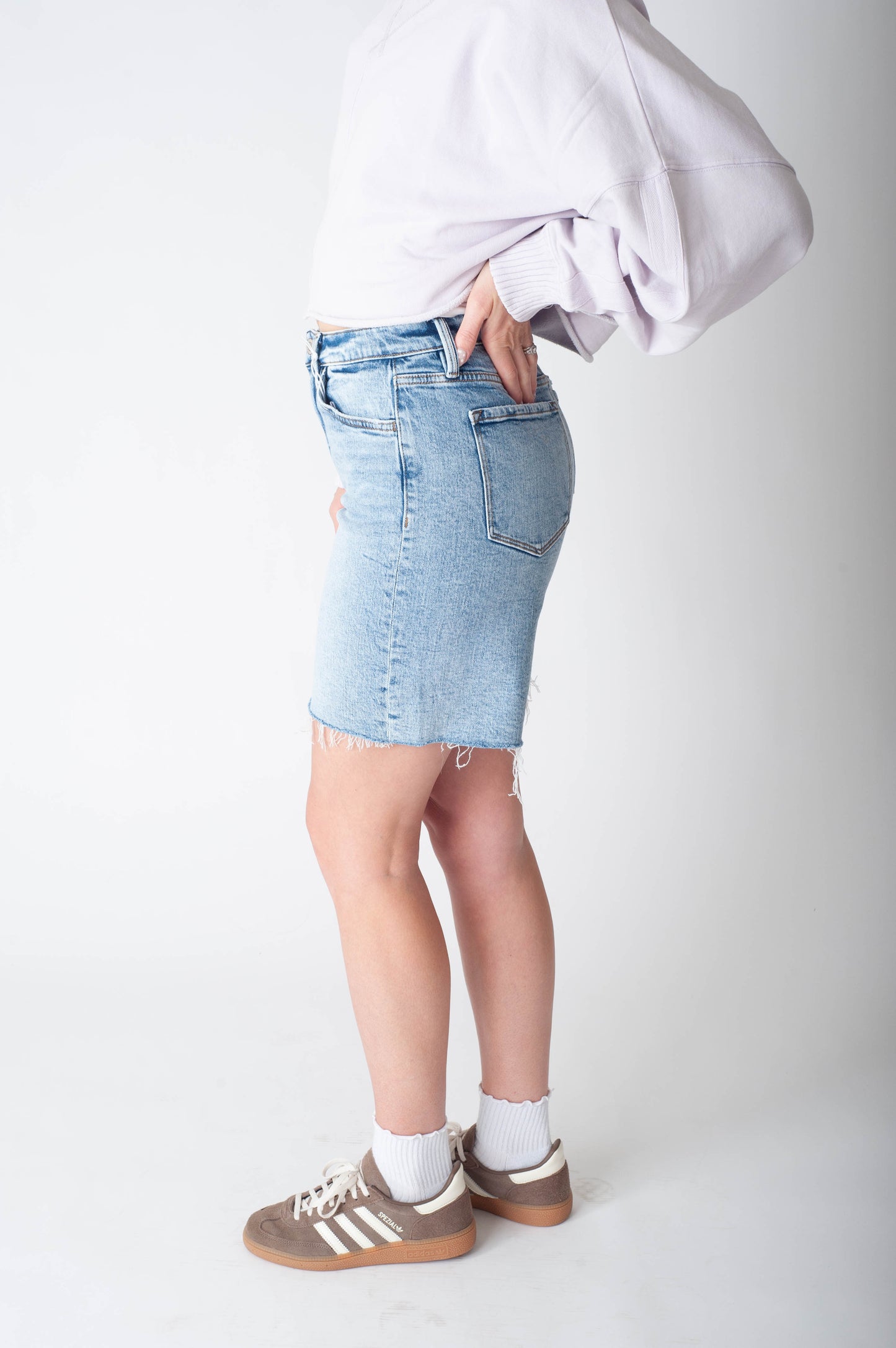 Women wearing long denim shorts and a purple sweater. 
