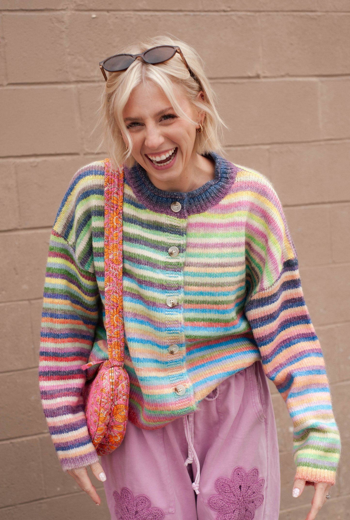 women wearing a rainbow stripe cardigan and pink wide leg sweatpants. 