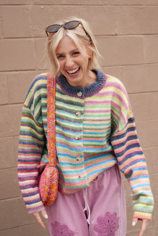 women wearing a rainbow stripe cardigan and pink wide leg sweatpants. 