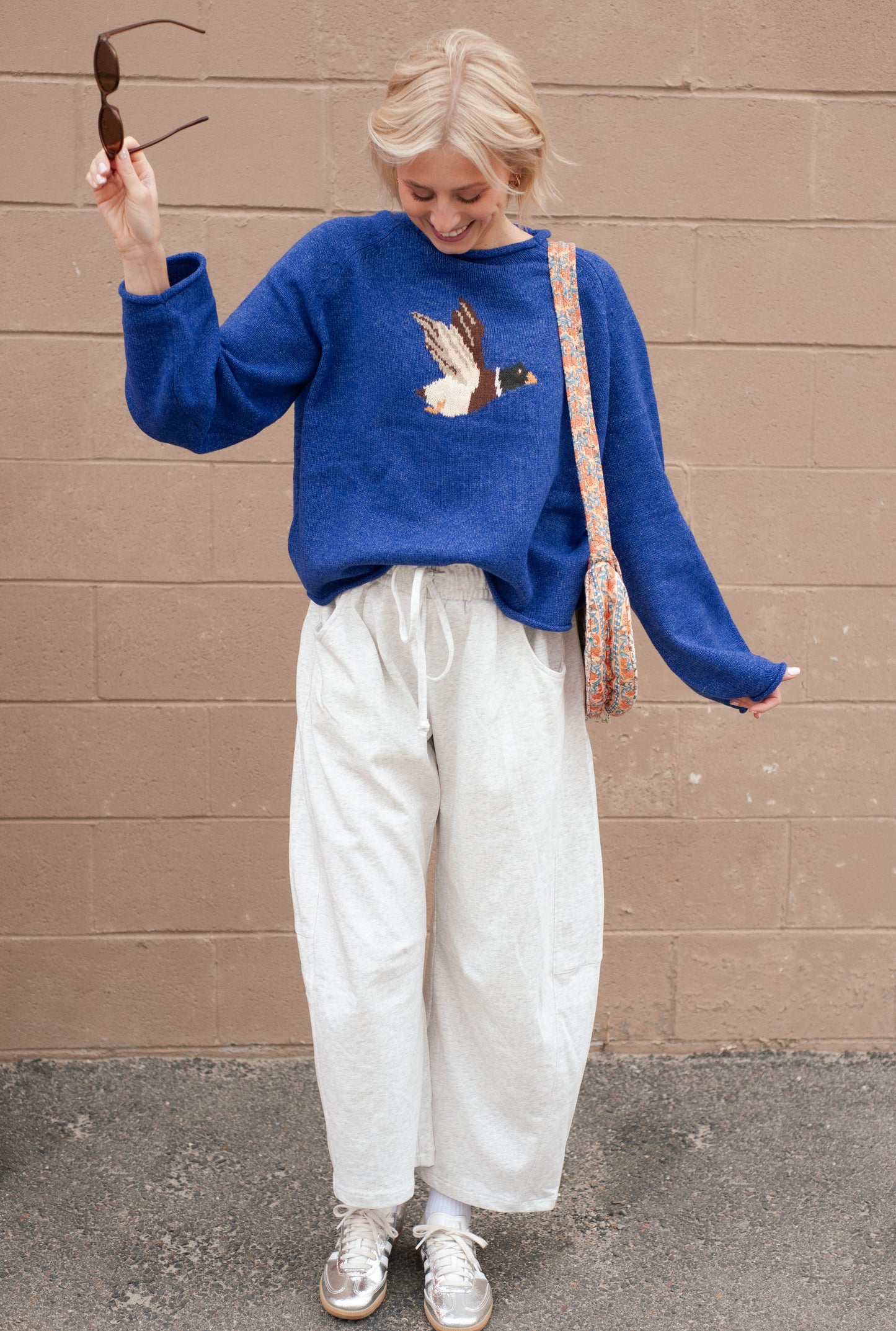 Women wearing a blue sweater with a duck print on it. 