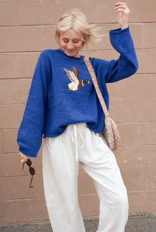 Women wearing a blue sweater with a duck print on it. 