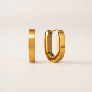 Gold hoop earrings on a light beige background