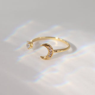 Gold ring with a crescent moon design on a light background