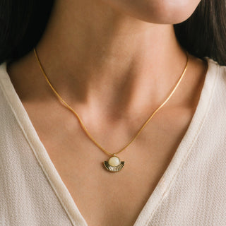 Gold necklace with a pendant worn by a person in a neutral setting